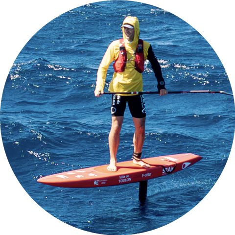 Rider in a hat and yellow vest on a foil board with a paddle